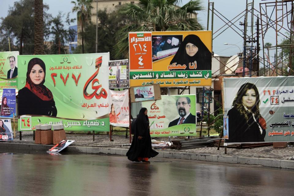 In this photo taken on April 14, 2014, an Iraqi woman passes by campaign posters in Baghdad, Iraq. The vibrant posters promise jobs, prosperity and security coming from Iraq’s first parliamentary elections since U.S. troops withdrew from the country, but so far, voters have only dim hopes as sectarian bloodshed rages unstopped. (AP Photo/Khalid Mohammed)