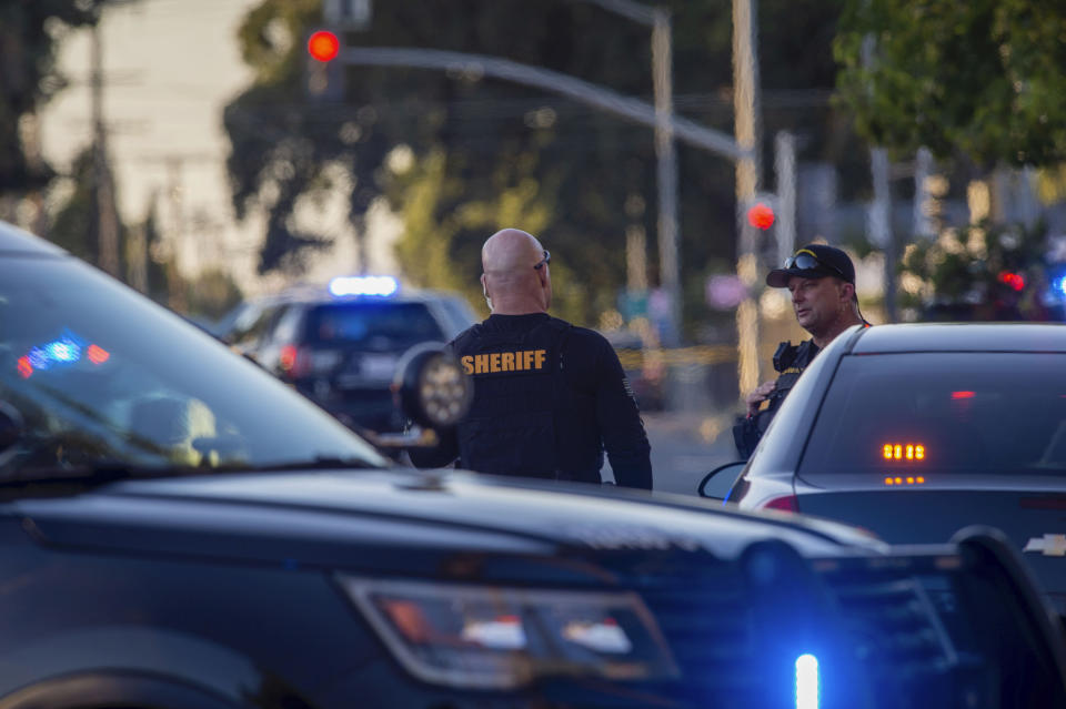 Sacramento County Sheriff's Department deputies talk, Wednesday, June 19, 2019, on Grove Avenue in Sacramento, Calif., where an armed subject fired on police officers. (Daniel Kim/The Sacramento Bee via AP)