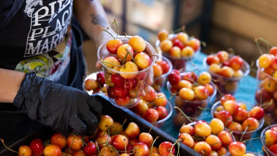 A worker arranges Rainier cherries at a fruit stand in the Pike Place Market in Seattle, Washington, US, on Thursday, July 4, 2024. 