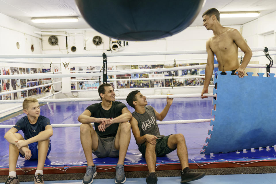 From left, Jewish boxers Noam Goldstein, 15, and Daniel Ilyushonok, 18, talk with Arab boxers Sofian el Okby, 17, and Safi Shabam, 16, while working out together at the Maccabi Lod Boxing Club in the mixed Arab-Jewish town of Lod, central Israel, Wednesday, May 26, 2021. Club coach Yaacov Wallach said both his Arab and Jewish boxers would check on him everyday during the recent clashes when the club was closed to see if everything was ok. "This club is open to everyone," said Wallach. "Here we are like family." (AP Photo/David Goldman)