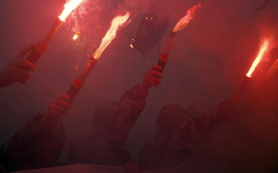 Volunteers with the right-wing paramilitary Azov National Corps brandish flares and hold a banner reading 'Scammers in jail' during a rally in front of the office of the General Prosecutor of Ukraine in Kiev, Ukraine, Wednesday, Feb. 27, 2019. President of Ukraine Petro Poroshenko suspended from office Oleh Hladkovsky, First Deputy Secretary of the National Security and Defense Council, pending the probe opened following a journalistic investigative report on corruption. (AP Photo/Efrem Lukatsky)