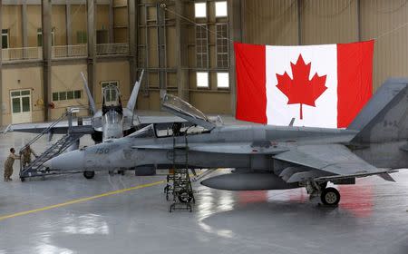 FILE PHOTO: Members of the Canadian Forces push a ladder up to a Canadian F-18 Hornet fighter at the Camp Patrice Vincent section of a military base in Kuwait May 3, 2015. REUTERS/Chris Wattie/File Photo