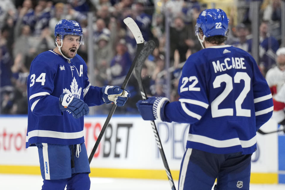 Toronto Maple Leafs center Auston Matthews (34) celebrates his last minute empty net goal against the Florida Panthers with teammate defenseman Jake McCabe (22) during the third period of an NHL hockey game in Toronto on Monday, April 1, 2024. (Frank Gunn/The Canadian Press via AP)