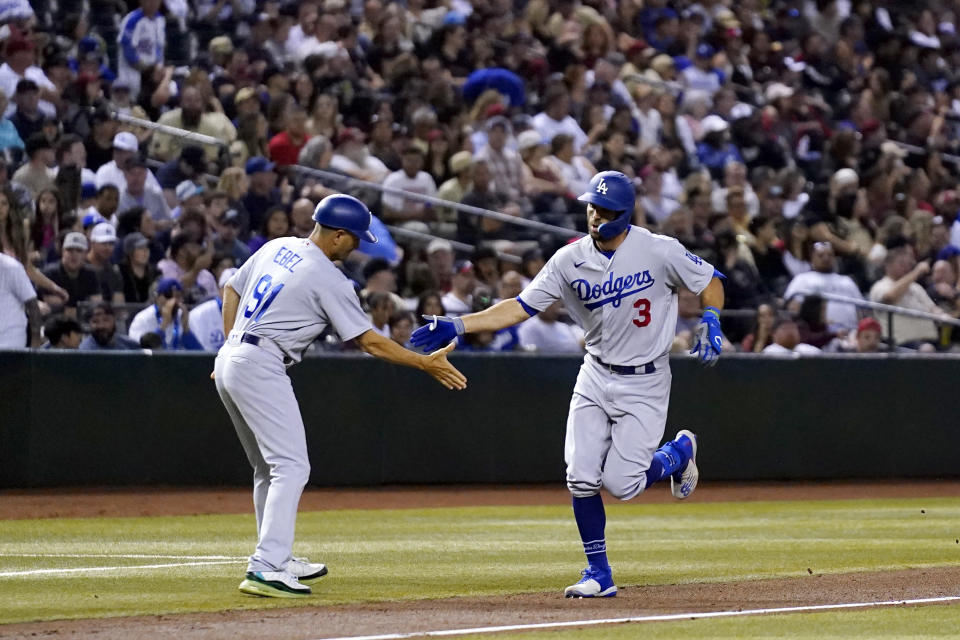 Los Angeles Dodgers' Chris Taylor (3) shakes hands with third base coach Dino Ebel after Taylor hit a home run against the Arizona Diamondbacks during the fourth inning of a baseball game Friday, April 7, 2023, in Phoenix. (AP Photo/Ross D. Franklin)