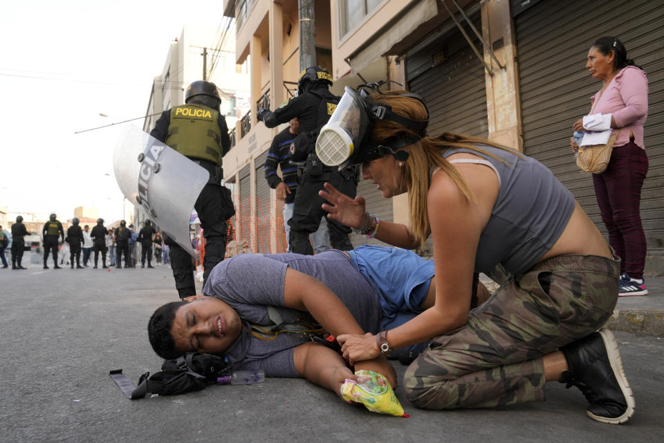 A woman tends to an anti-government protester who fell during a march against President Dina Boluarte in Lima, Peru, Thursday, Jan. 19, 2023. Protesters are seeking immediate elections, the resignation of Boluarte, the release from prison of ousted President Pedro Castillo and justice for protesters killed in clashes with police. (AP Photo/Martin Mejia)