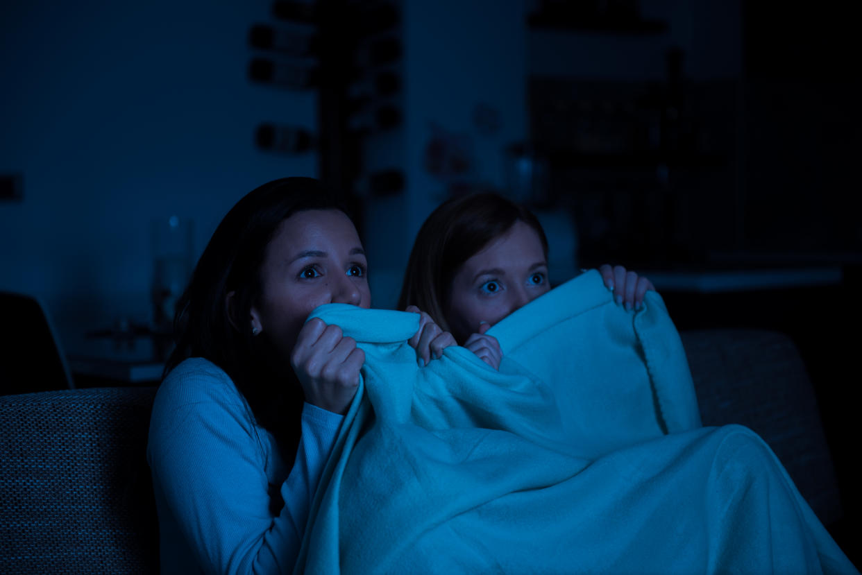 Two women watching horror movie on a tv together