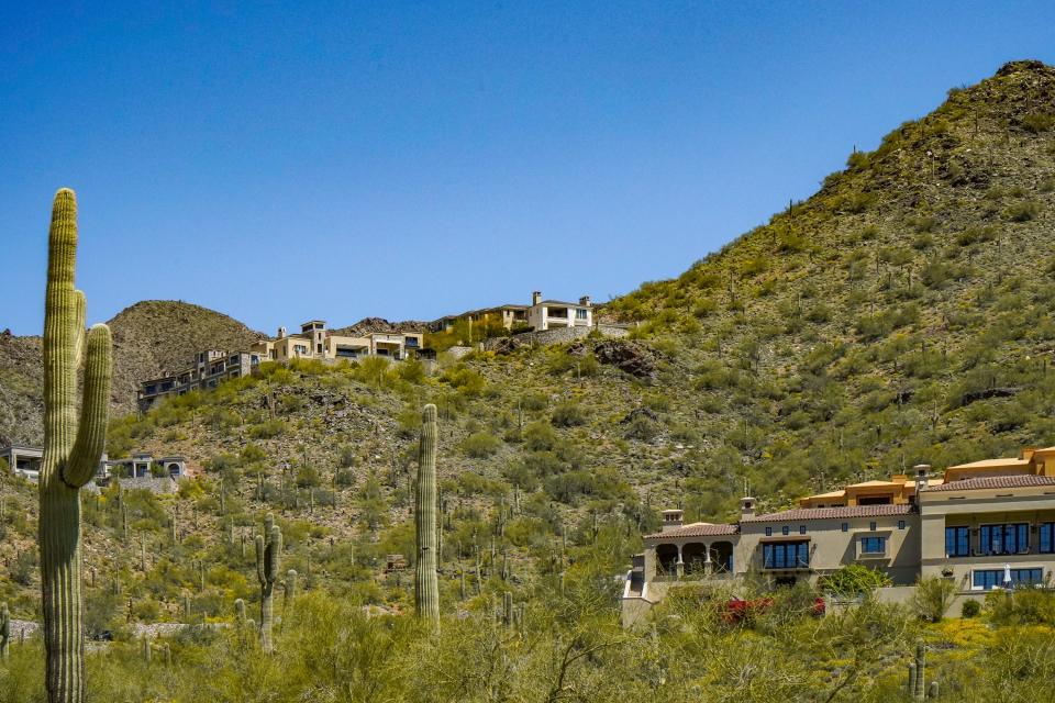 Mansions off of a winding road on a mountain dotted with bushes and cacti in DC Ranch in Scottsdale