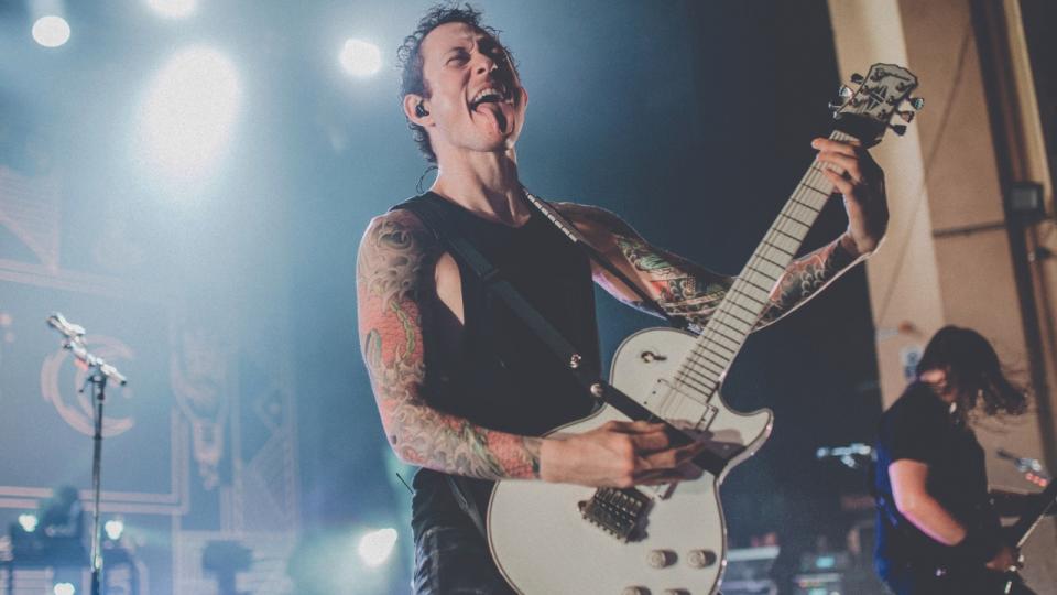 Matt Heafy plays a Les Paul guitar on stage with a fretwrap around the headstock