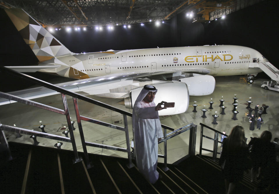 FILE - In this Dec. 18, 2014, file photo, an Emirati man takes a selfie in front of a new Etihad Airways A380 in Abu Dhabi, United Arab Emirates. Abu Dhabi-based Etihad Airways said Thursday, Feb. 14, 2019, that it has restructured planned airplane purchases from Airbus and Boeing as the government-owned carrier faces financial turbulence. (AP Photo/Kamran Jebreili, File)