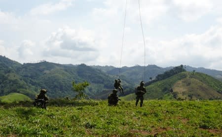 Soldiers disembark from a helicopter as workers destroy coca plants during an eradication operation at a plantation in Taraza