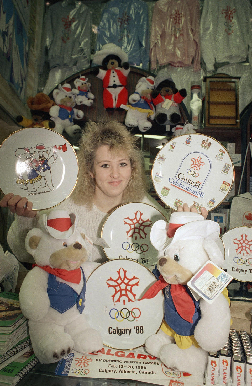 Allison McAbe is framed by all kinds of souvenirs in a Calgary, Alberta, shop on Feb. 7, 1988. (AP Photo/Michel Lipchitz)