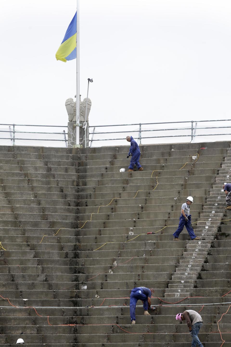 In this Tuesday, July 2, 2013 photo, workmen repair on the stadium at the West Side Tennis Club in the Queens section of New York. The Beatles. The Rolling Stones. Frank Sinatra. Jimi Hendrix. Bob Dylan. They’ve all held court at the more than century-old West Side Tennis Club in Queens’ Forest Hills neighborhood - for six decades the site of the U.S. Open Tennis Championships. Plans are now in the works for the grassy lawn to come alive again with the sound of music, starting with a concert featuring the British band Mumford & Sons, to be followed by a lineup of world-class musicians. (AP Photo/Seth Wenig)