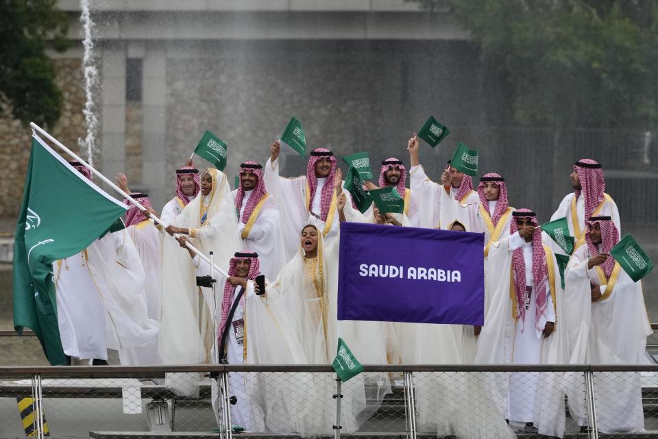 The Saudi Arabian team waves flags on a boat in Paris, France, during the opening ceremony of the 2024 Summer Olympics, Friday, July 26, 2024. / Credit: Kirsty Wigglesworth / AP