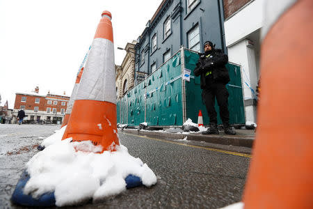 A police officer stands next to screening surrounding a restaurant which was visited by former Russian intelligence officer Sergei Skripal and his daughter Yulia before they were found on a park bench after being poisoned in Salisbury, Britain, March 19, 2018. REUTERS/Peter Nicholls