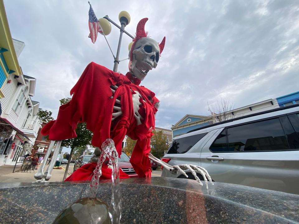 A skeleton, dressed as a devil, can be seen getting a drink from a water fountain in downtown Harbor Springs.