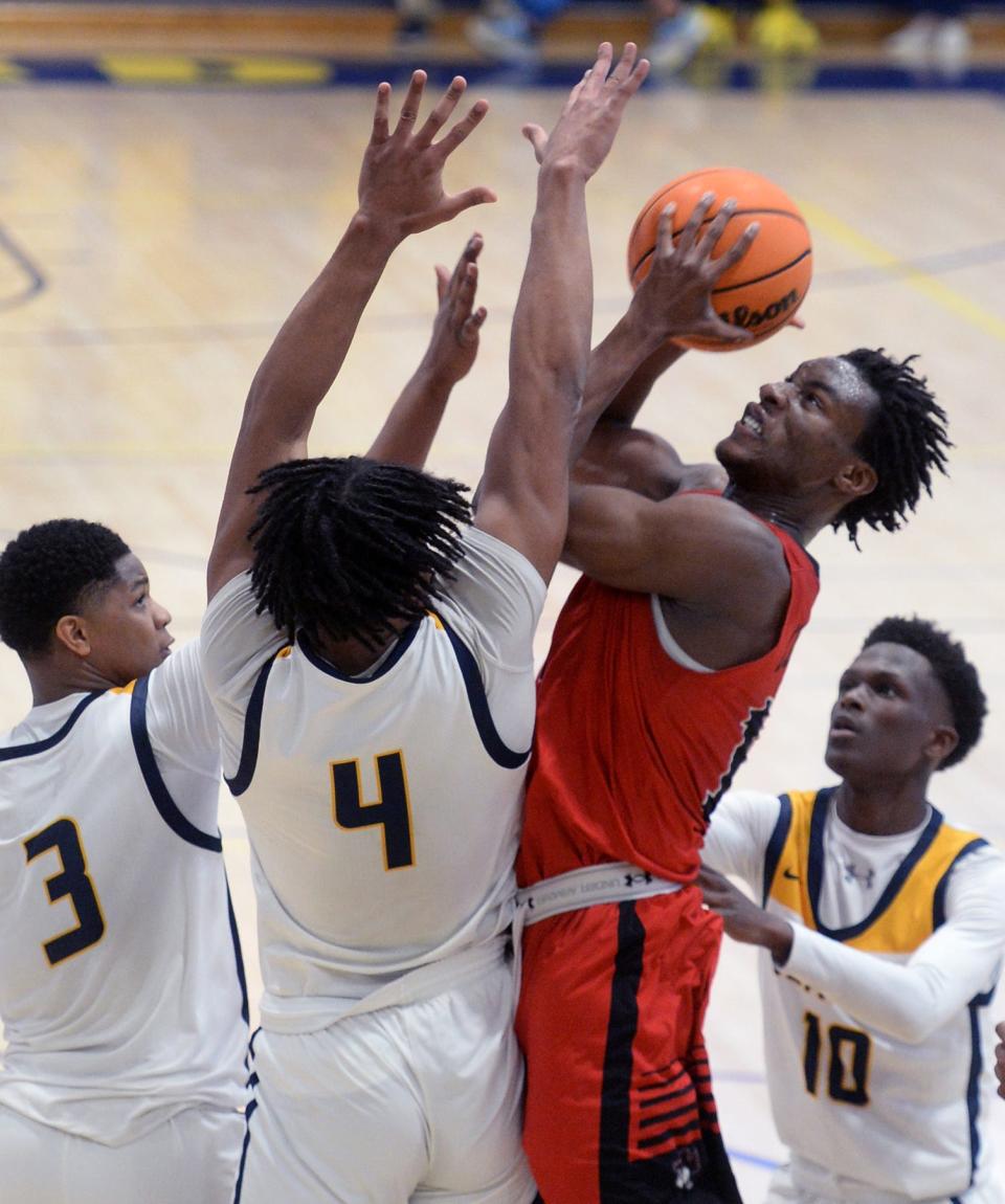 Emanuel Vonhm of William Penn takes a shot close under the basket with Seaford's Kashmier Wise (3) and Aviyon Matthews trying to block.