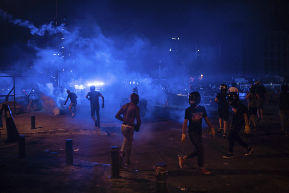 Protesters run from tear gas fired by police forces during an anti-government protest following Tuesday's massive explosion which devastated Beirut, Lebanon, Sunday, Aug. 9. 2020. (AP Photo/Felipe Dana)