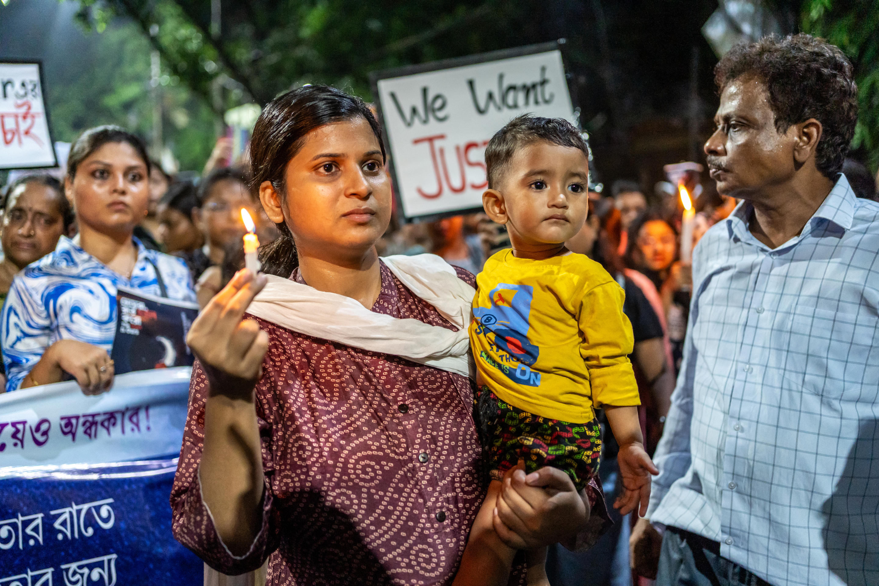 A woman carries her child and holds a candle as a sign of homage and a demand for justice. 