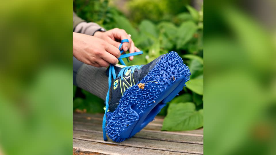 Inspired by nature, the 3D-printed blue outsole, shown here over a running shoe, could help disperse seeds and promote rewilding. - Tom Mannion