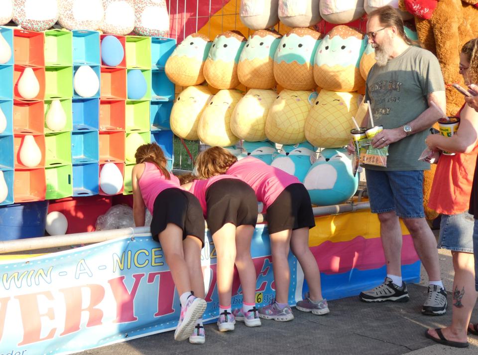 Three girls pick out prizes at a carnival game on Thursday evening on the midway at the 2022 Crawford County Fair.
