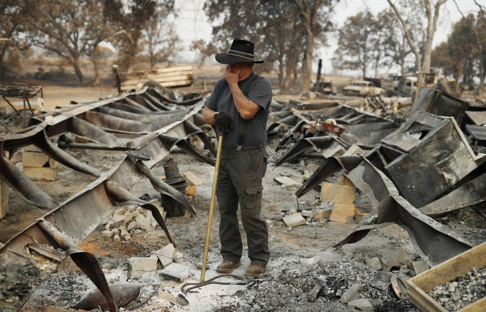 Ed Bledsoe tries to hold back tears as he searches through what remains of his home, Monday, Aug. 13, 2018, in Redding, Calif. Bledsoe's wife, Melody, great-grandson James Roberts and great-granddaughter Emily Roberts were killed at the home in the Carr Fire. (AP Photo/John Locher)