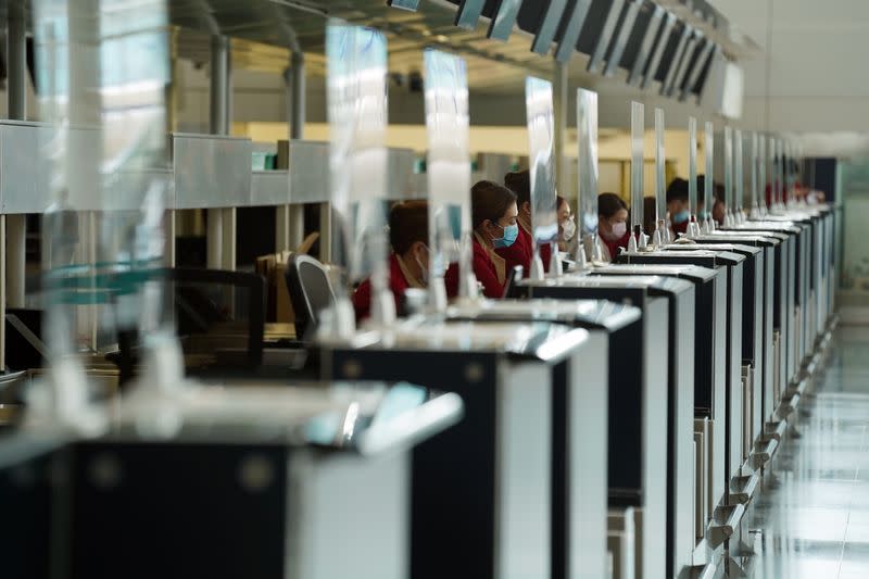 Cathay Pacific employees are seen behind counters with glass dividers at Hong Kong International Airport in Hong Kong