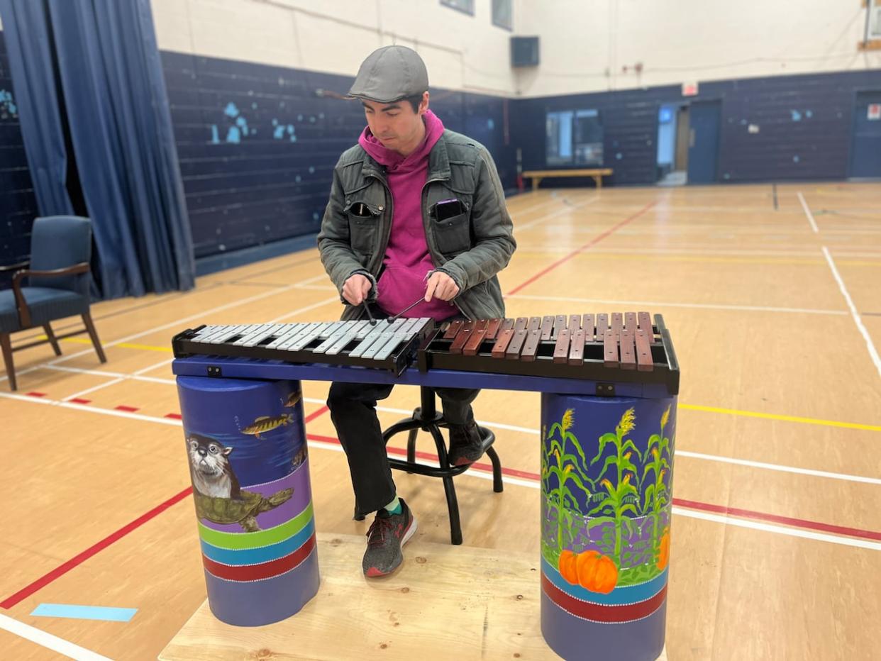 Kahnawà:ke resident Dennen Phillips tries out the xylophone and glockenspiel, which will be among the percussion instruments featured in the musical park. (Ka’nhehsí:io Deer/CBC - image credit)