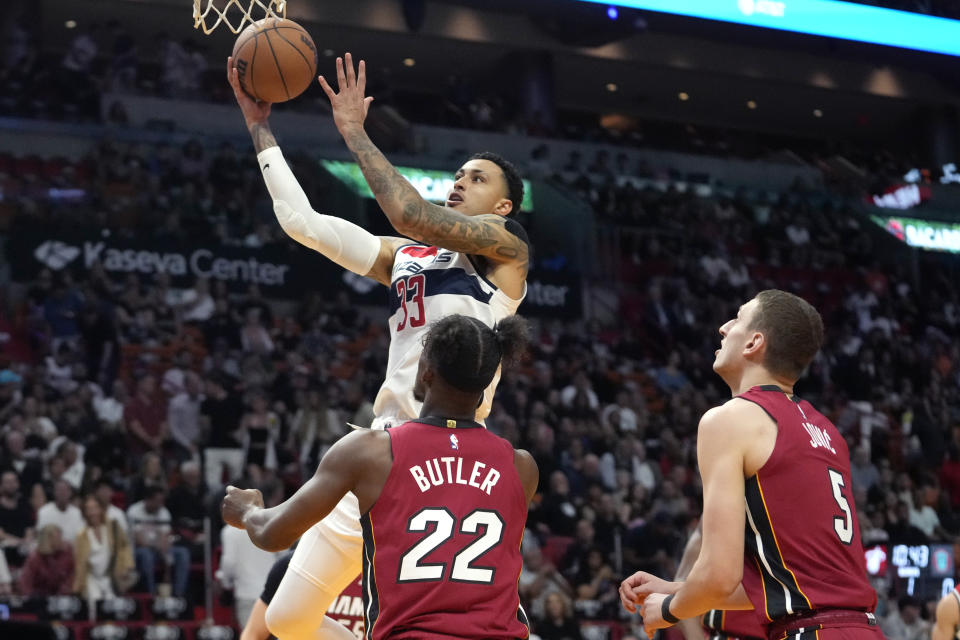 Washington Wizards forward Kyle Kuzma goes to the basket past Miami Heat forward Jimmy Butler (22) and forward Nikola Jovic during the first half of an NBA basketball game, Sunday, March 10, 2024, in Miami. (AP Photo/Lynne Sladky)