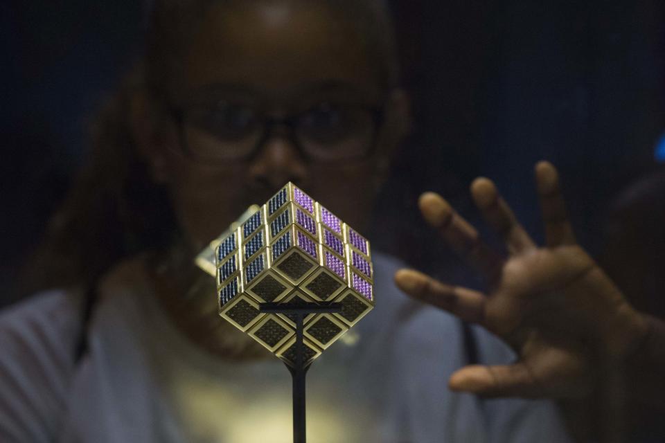 A girl looks at the world's most expensive Rubik's Cube on display during an exhibition, while people attend the National Rubik's Cube Championship at Liberty Science Center in Jersey City