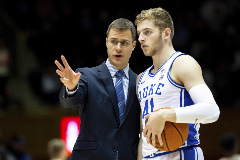 FILE - In this Dec. 19, 2019, file photo, Duke associate head coach Jon Scheyer, left, speaks with Jack White (41) during an NCAA college basketball game against Wofford in Durham, N.C. Duke Hall of Fame coach Mike Krzyzewski will coach his final season with the Blue Devils in 2021-22, a person familiar with the situation said Wednesday, June 2, 2021. The person said former Duke player and associate head coach Jon Scheyer would then take over as Krzyzewski's successor for the 2022-23 season. (AP Photo/Ben McKeown, File)