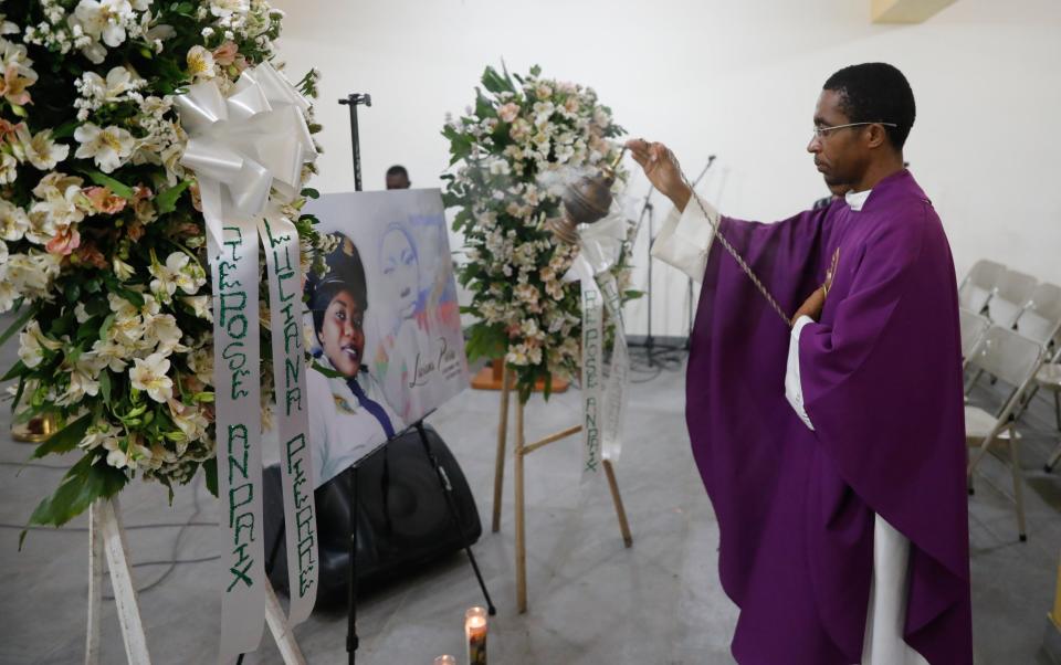 A priest swings incense in front of a photo of police officer Luciana Pierre during her memorial in Port-au-Prince, Haiti, Tuesday, March 12, 2024. According to the family, Pierre was killed in an attack by armed gangs the previous week and her body has not been recovered. (AP Photo/Odelyn Joseph)