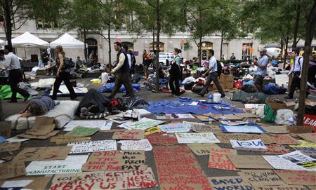 Morning commuters walk past Occupy Wall Street campaign protesters sleeping in Zuccotti Park, near Wall Street in New York in this September 27, 2011 file photo. As Occupy's two-year anniversary approaches on September 17, the movement that once captivated national attention has largely faded. REUTERS/Brendan McDermid/Files
