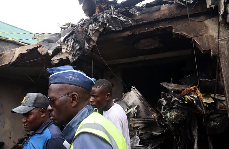 Congolese police and civilians gather at the site where a Dornier 228-200 plane operated by local company Busy Bee crashed into a densely populated neighborhood in Goma