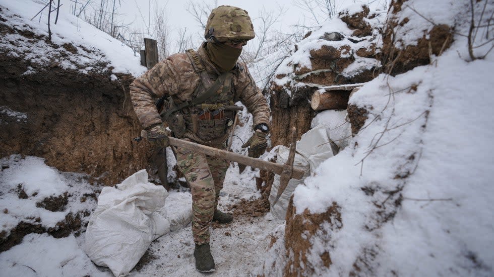 An Ukrainian serviceman works to fix a trench that was damaged by a mortar strike less than 100 meters from Russian separatists positions on Friday, Jan. 28, 2022