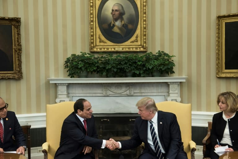 Translators watch as Egypt's President Abdel Fattah al-Sisi (L) and US President Donald Trump shake hands in the Oval Office before a meeting at the White House April 3, 2017