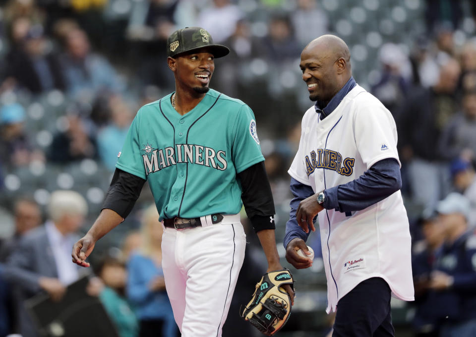 FILE - Seattle Mariners' Dee Gordon, left, laughs with former Mariners player Harold Reynolds after Reynolds tossed out the ceremonial first pitch before the team's baseball game against the Minnesota Twins on May 17, 2019, in Seattle. Harold Reynolds and Ibañez will be the managers for the All-Star Futures Game in Seattle in July. (AP Photo/Elaine Thompson)