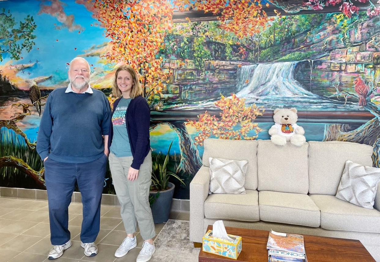 John Andrews-Carrico and Katie Tremel stand in front of a mural at Cancer Support Community South Central Indiana's Bloomington center that was created by Adam Long. Tremel is program manager at the center; Andrews-Carrico is a participant.