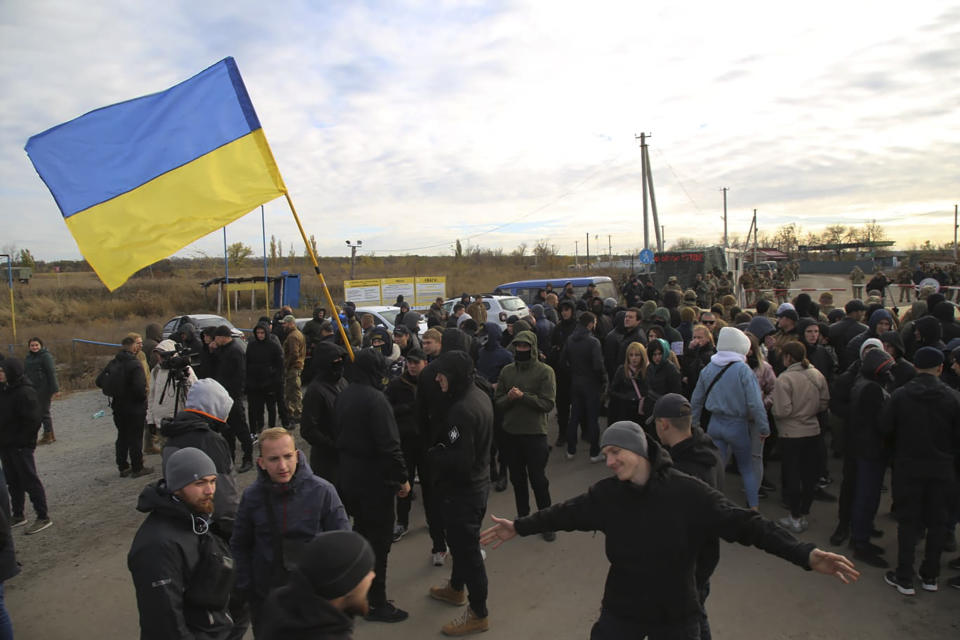 Ukrainian army veterans and volunteers wave the national flag at a checkpoint near the village of Zolote in the Luhansk region, Ukraine, Wednesday, Oct. 9, 2019. Several dozen activists arrived on Wednesday in the area of a much anticipated pullback of heavy weaponry from both sides of the de facto border, saying that they would try to prevent it from happening. (AP Photo/Bohdan Kutepov)