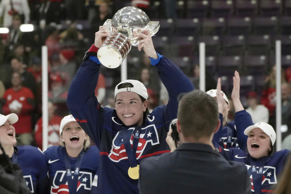 FILE - United States forward Hilary Knight, center, holds the cup as she celebrates with teammates after defeating Canada in the gold medal game at the women's world hockey championships in Brampton, Ontario, April 16, 2023. Hilary Knight, Marie-Philip Poulin and their United States and Canadian national hockey team contemporaries now have a firm idea of where they’ll be playing in January. The newly founded Professional Women's Hockey League unveiled its Original Six franchises on Tuesday, Aug. 29, with franchises based in NHL markets — three in the United States and three in Canada — with track records of supporting the women’s game. (Nathan Denette/The Canadian Press via AP, File)