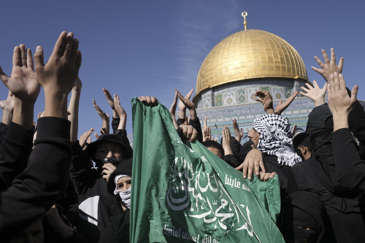 Palestinians holding a Hamas flag, protest by the Dome of the Rock Mosque at the Al-Aqsa Mosque compound in the Old City of Jerusalem, Friday, Jan. 27, 2023. The protest was a day after the deadliest Israeli raid in decades and raised the prospect of a major flare-up in fighting. (AP Photo/Mahmoud Illean)