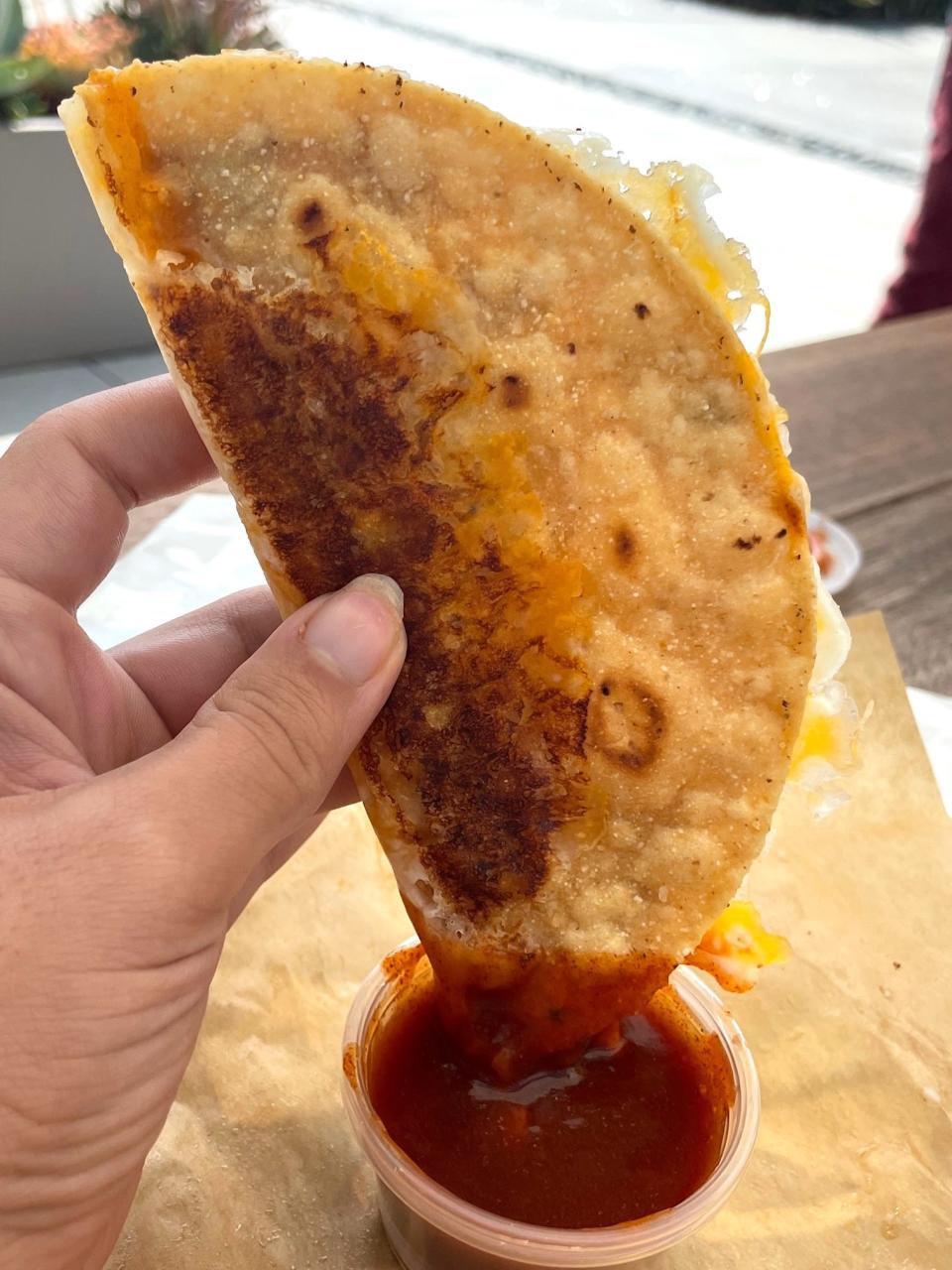 Taco Bell's Grilled Cheese Dipping Taco dipped in red sauce