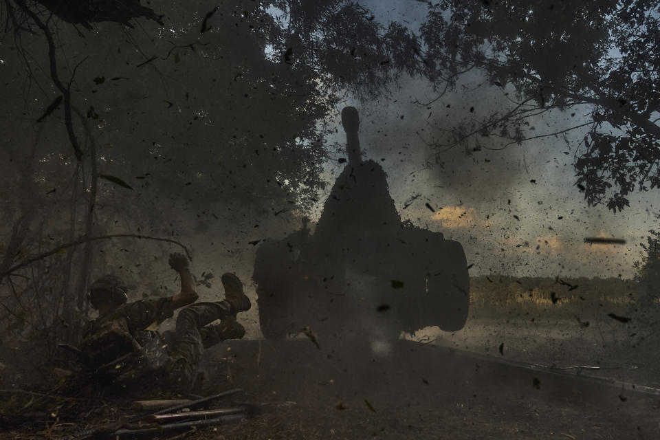 A Ukrainian policeman of a special police unit falls as he fires a D-30 cannon towards Russian positions at the front line, near Kreminna, Luhansk region, Ukraine, Friday, July 7, 2023. (AP Photo/Libkos)