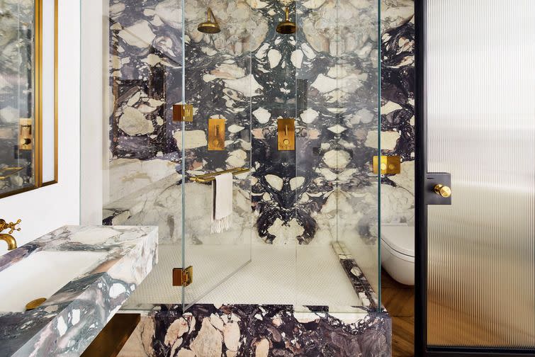<p>All-over marble wraps this beautiful bathroom vanity and shower that's designed by Nina Garbiras of Fig NYC. To keep things clean, use matching finishes like antique brass to keep the room cohesive.</p>