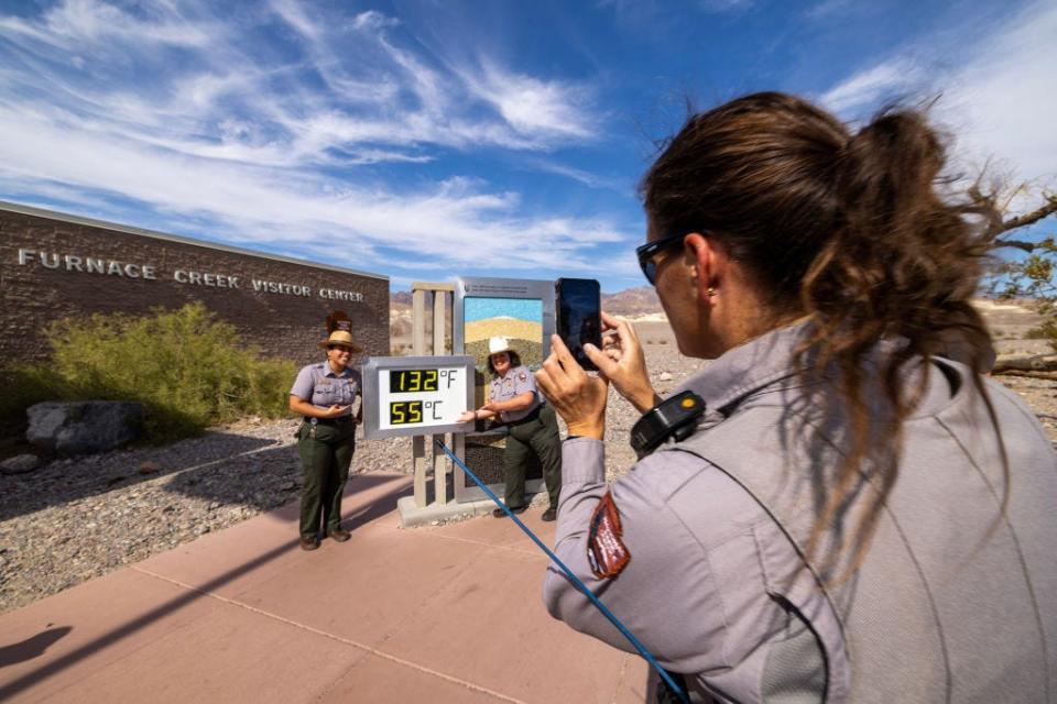 Park rangers pose for pictures near an unofficial thermometer at Death Valley's Furnace Creek Visitor Center.