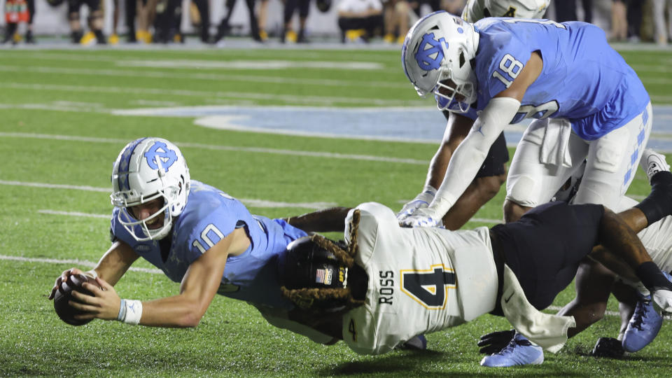 North Carolina quarterback Drake Maye (10) dives for additional yards after being brought down by Appalachian State safety Nick Ross (4) as North Carolina tight end Bryson Nesbit (18) assists during the second half of an NCAA college football game, Saturday, Sept. 9, 2023, in Chapel Hill, N.C. (AP Photo/Reinhold Matay)
