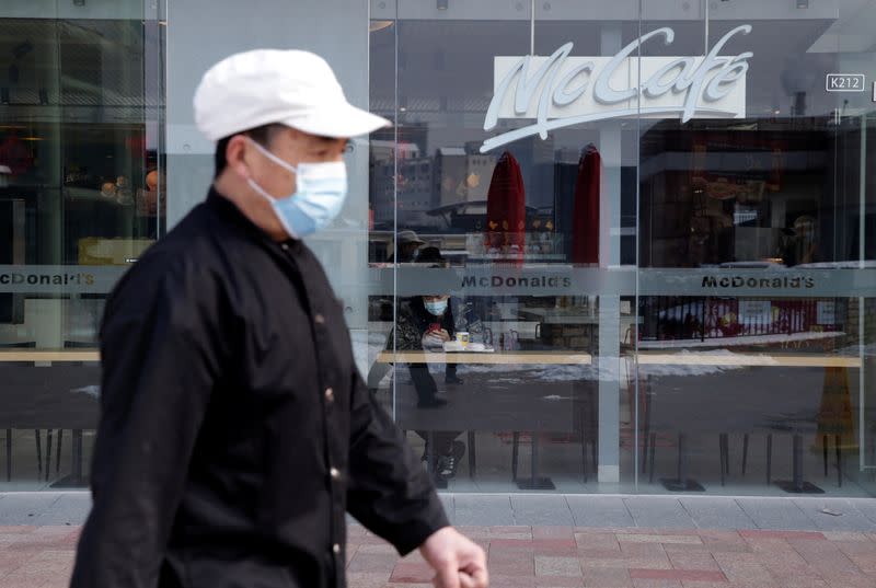 FILE PHOTO: Man wearing a face mask walks past a McDonald's store at a shopping area in Beijing