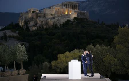 Greek Prime Minister Alexis Tsipras hugs French President Emmanuel Macron after delivering a speech atop the Pnyx Hill as the Acropolis hill with the ancient Parthenon temple is seen in the background in Athens, Greece, September 7, 2017. REUTERS/Alkis Konstantinidis