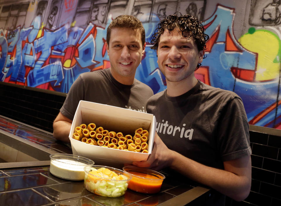 Culinary Director Barry Frish, left, and owner and manager Brad Holtzman of Taquitoria, on New York's Lower East Side, pose with a box of Buffalo chicken taquitos, Tuesday, Jan. 14, 2014. Taquitoria, a shop that serves only the deep-fried, cigar-like tortillas called taquitos, offers 40-piece boxes of the Buffalo chicken taquitos throughout football season. On Super Bowl game day they expect to do 99 percent of their business for takeout. (AP Photo/Richard Drew)