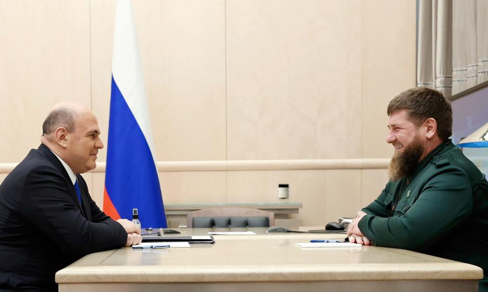 Two men sit across each other at a table.