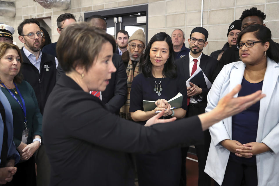 State and local officials toured the Melnea A. Cass Recreational Complex Wednesday, Jan. 31, 2024, while Governor Maura Healey, left, spoke to officials and Boston Mayor Michelle Wu, center, looks on taking notes, in the Roxbury neighborhood of Boston. The facility will house over 300 migrants. (John Tlumacki/The Boston Globe via AP, Pool)